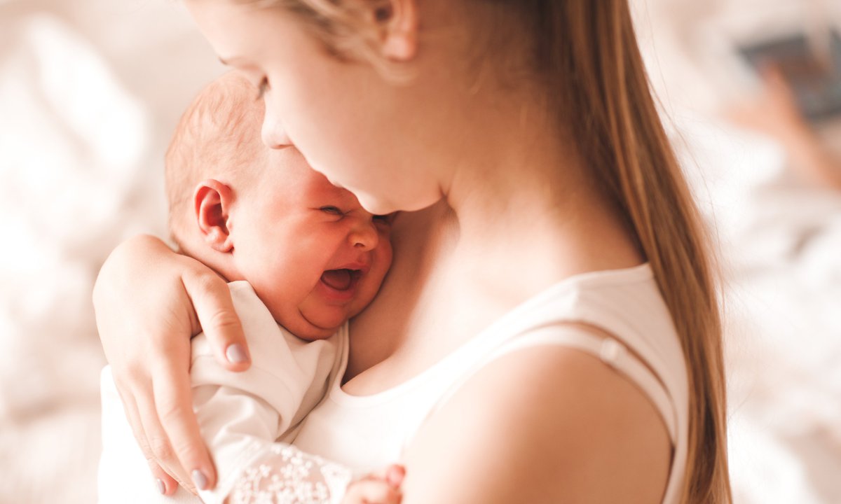 bebelus care plange strans in brate de mama lui