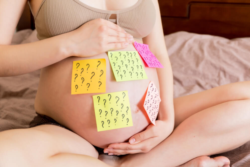 imagine cu mamica gravida care are pe burtica mai multe post-it-uri cu semnul intrebarii care semnifica dezicia de a pune un nume copilului din burtica