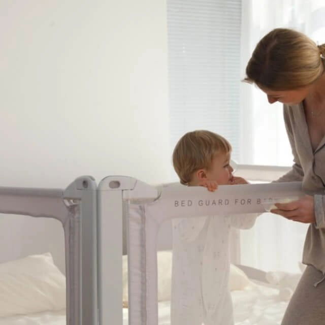 imagine cu bebe in pat si mama langa patul are o bariera de protectie pentru copii