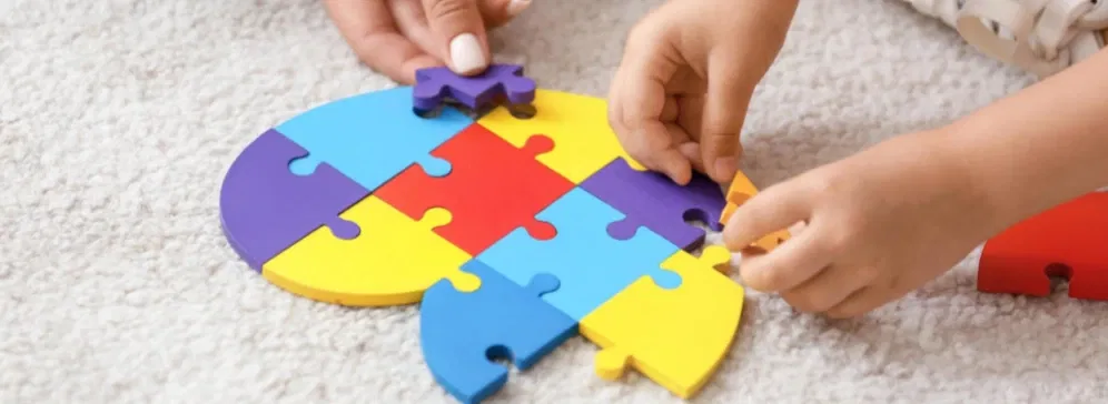 maini de copil care construiesc un puzzle colorat din lemn