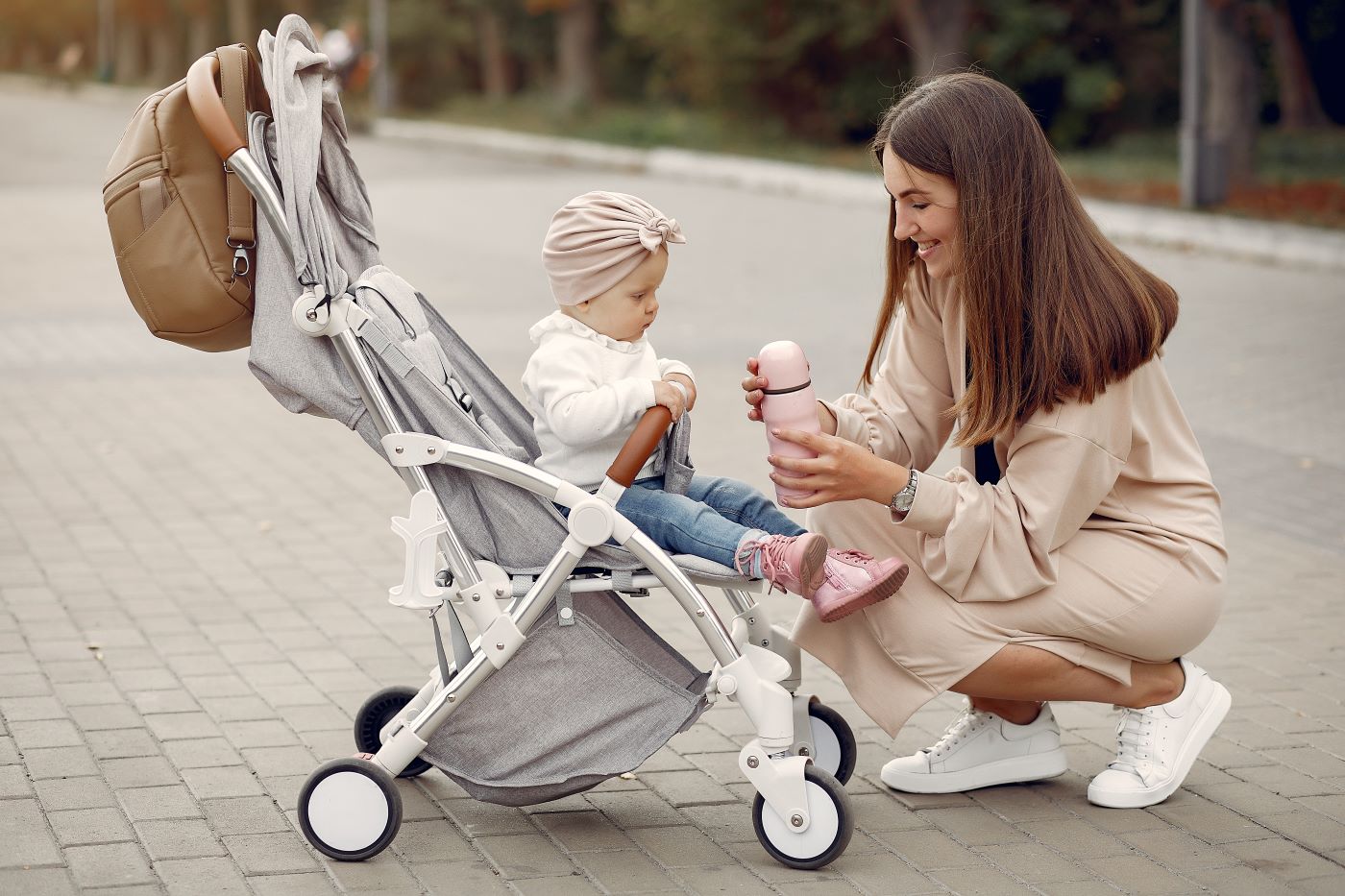 mama zambitoare si bebelus in carucior care primeste un biberon