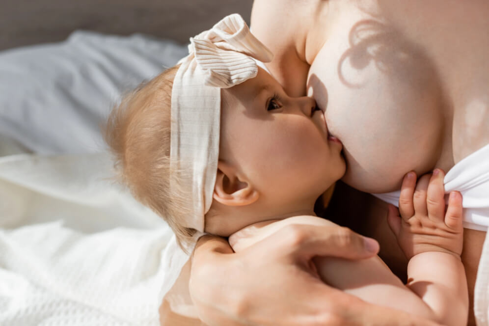 bebe care mananca lapte in bratele mamei