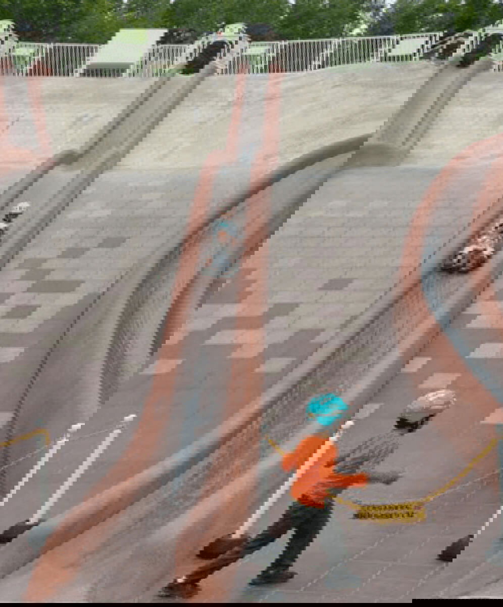 imagine cu locul de joaca takino hillside din Japonia cu tobogan de piatra si copii care sa dau pe o placa