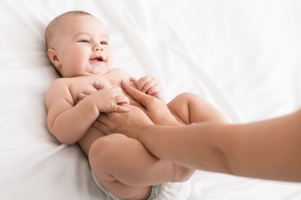 bebelus vesel cu mainile mamei pe el 