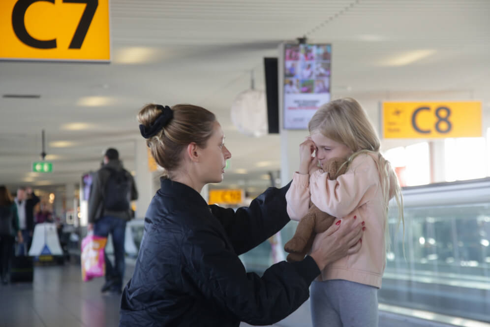 fetita care cere ajutorul unei stewardesa in aeroport pentru a o ajuta sa ajunga la mama ei