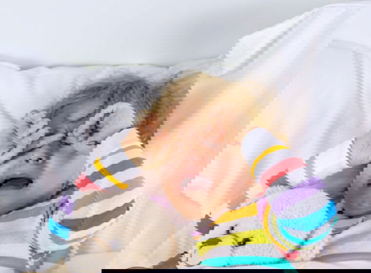 copil care sta in patut si plange 