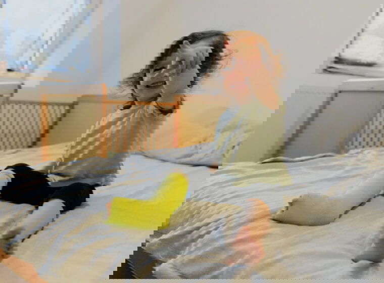 copil mic cu piciorul in ghips care sta in pat