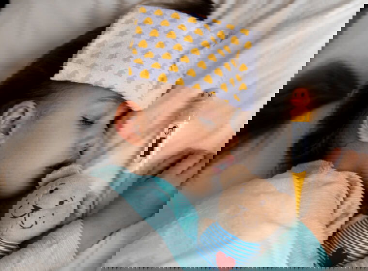 fetita care se simte rau si sta in pat cu termometru langa si cu ursuletul in brate si cu o fasa umeda pe cap pentru temperatura