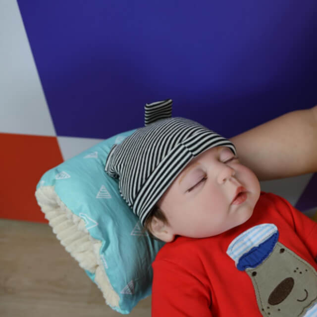 bebelus care sta cu capul pe o perna de alaptat