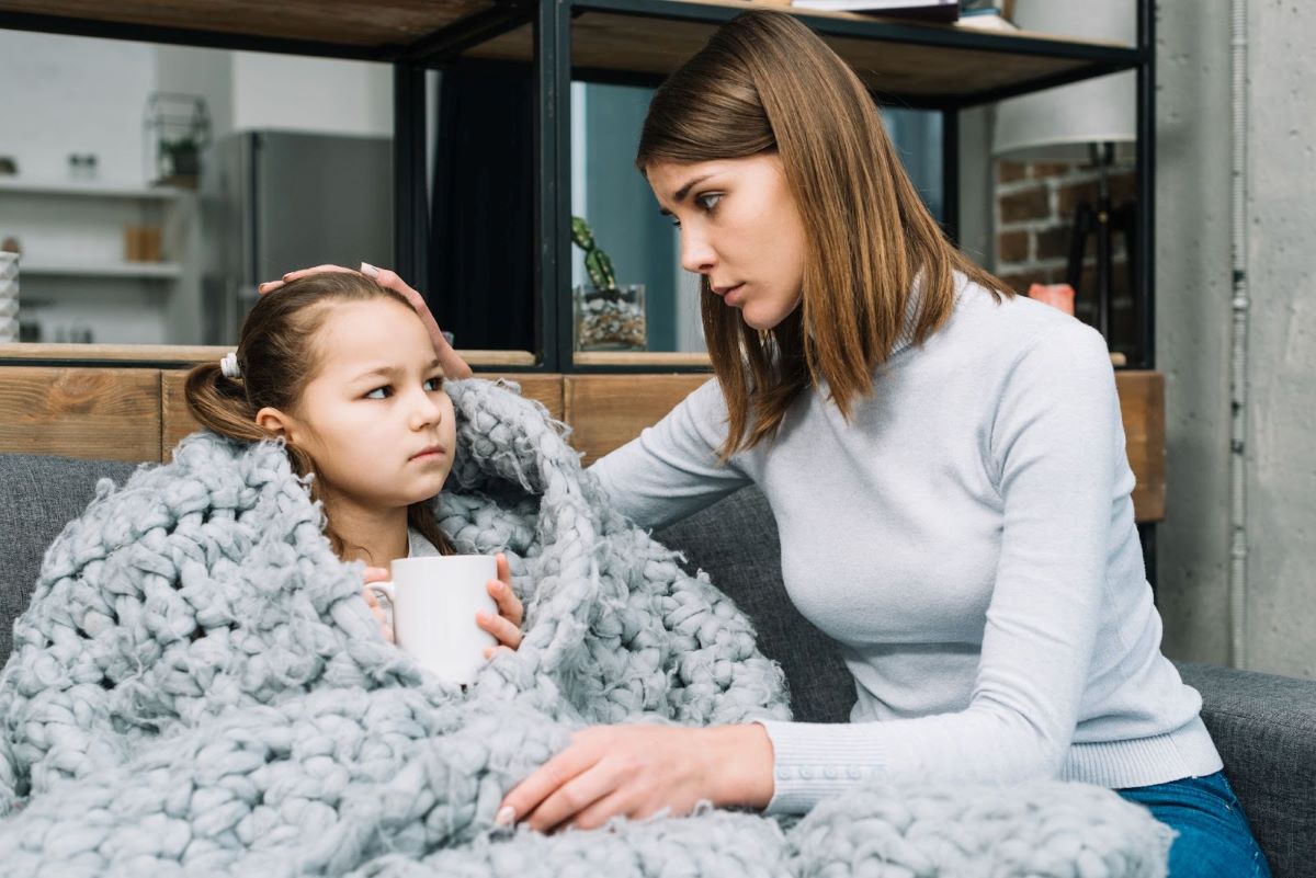 fetita bolnava ingrijita de mama ei, bea un ceai fierbinte