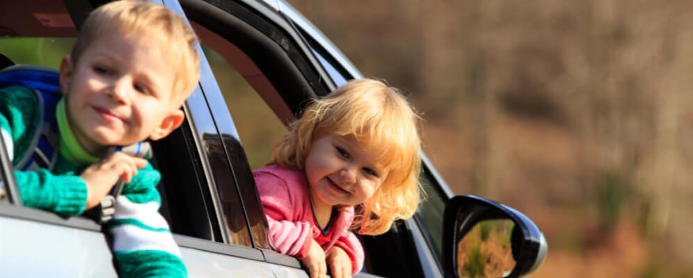 fetita si baietel in masina cu capul scos afara