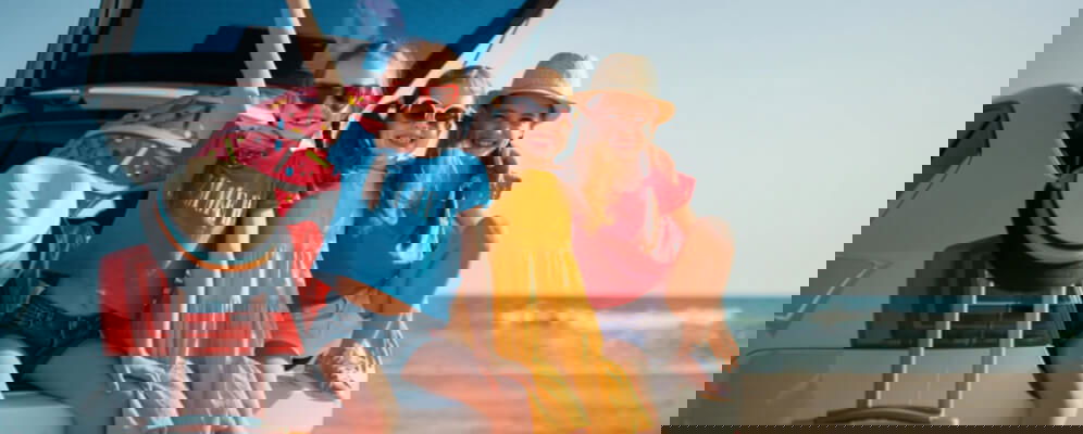 trei fete care stau pe portbagajul masinii 