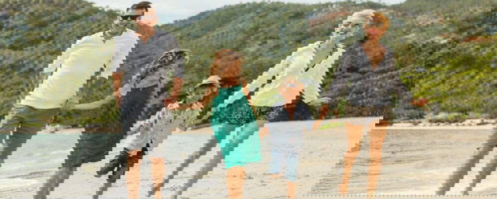 familie care se tine de mana pe plaja, din tata doi copii si mama 