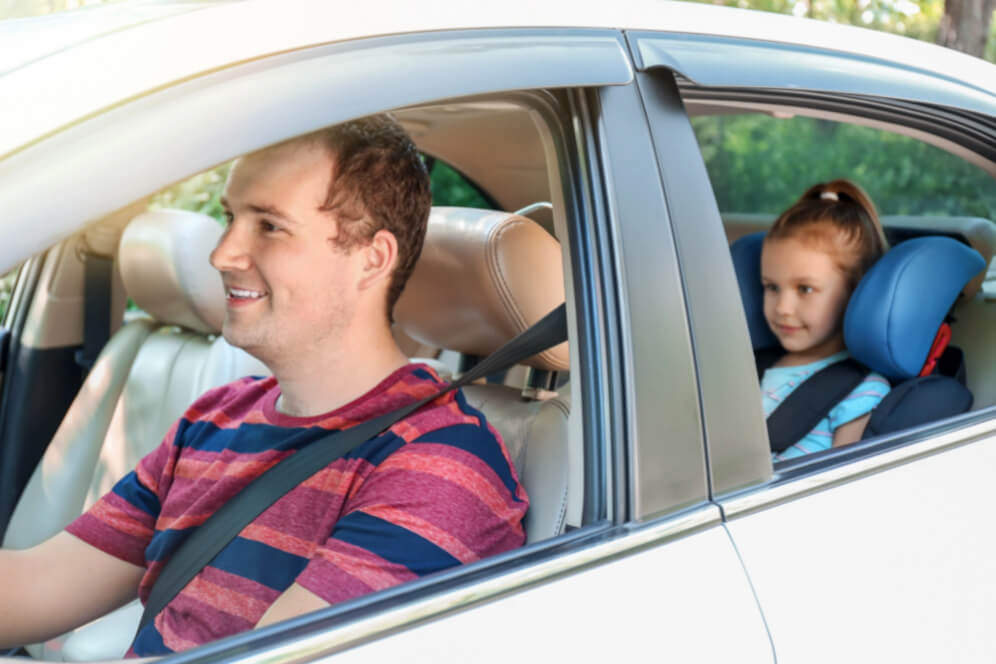 masina cu tatal la volan si fetita in spate pe scaunul de copil cu centura pusa