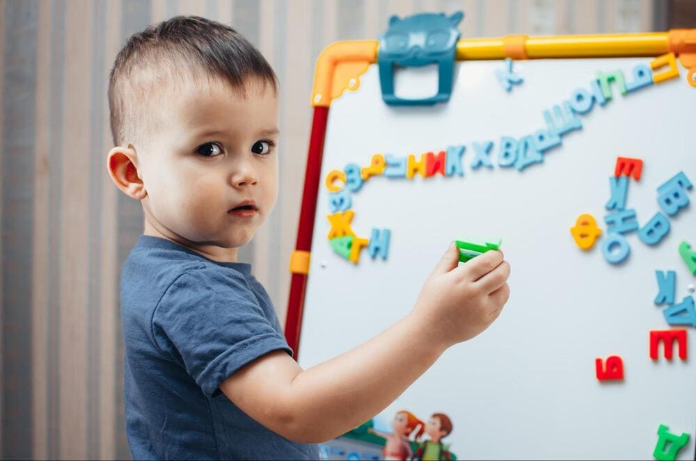 copil se joaca cu magneți alfabet