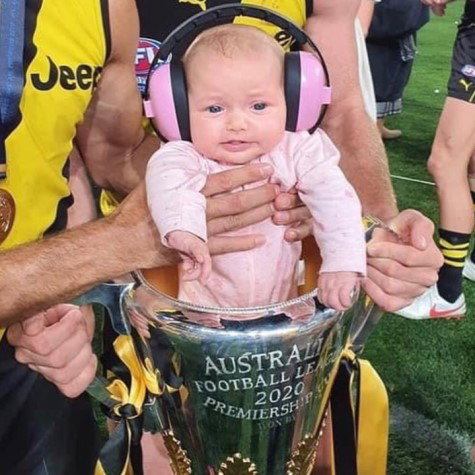 bebelus cu casti antifonice de protectie pe cap, care se afla intr-o cupa castigata la un meci