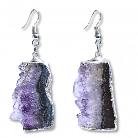 Descopera acum cum acesti cercei unici cu Ametist druzy pot aduce calm si echilibru spiritual in viata ta.  Cadoul Perfect pentru Cei Dragi: Acești cercei eleganți cu piatră naturală de Ametist druzy în formă neregulată sunt cadoul ideal pentru persoanele care apreciază bijuteriile unice și pline de semnificație. Sunt potriviți pentru aniversări, sărbători sau orice ocazie specială, oferind un simbol al păcii și echilibrului interior.  Beneficiile Ametistului: Ametistul druzy este cunoscut pentru capacitatea sa de a calma mintea și de a oferi protecție spirituală. Purtând acești cercei, vei experimenta o reducere a stresului și o creștere a clarității mentale. Această piatră este ideală pentru meditație și pentru a aduce un echilibru emoțional în viața de zi cu zi, promovând liniștea interioară.  Semnificație și Design: Acești cercei argintii cu Ametist druzy în formă neregulată nu sunt doar bijuterii frumoase, ci și simboluri ale echilibrului și protecției spirituale. Cu o dimensiune a pietrei de 3-3.5 cm și o greutate aproximativă de 10 grame per cercel, acești cercei sunt suficient de impunători pentru a atrage atenția, dar și confortabili pentru purtarea zilnică. Prinderea cu cârlig asigură o fixare sigură și ușor de utilizat.  Unicitate și Frumusețe: Pietrele de Ametist druzy utilizate sunt naturale, ceea ce înseamnă că fiecare pereche de cercei este unică. Pot exista mici variații de culoare și textură față de imaginile prezentate, conferind fiecărei perechi o frumusețe distinctă și un farmec aparte.  Zodii Compatibile: Ametistul este o piatră potrivită pentru zodiile Pești, Vărsător, Capricorn și Fecioară. Aceasta promovează calmul, echilibrul emoțional și protecția spirituală, fiind ideală pentru cei care doresc să își îmbunătățească conexiunea spirituală și să reducă stresul zilnic.  Cum Să Folosești Produsul în 3 Pași Simpli:  Deschide cârligul cerceilor și introdu-i în urechi. Fixează cârligul pentru a asigura o prindere sigură. Poartă-i zilnic pentru a beneficia de calmul și echilibrul oferite de Ametistul druzy. Specificații Tehnice:  Dimensiune piatră: 3-3.5 cm Greutate aproximativă per cercel: 10 grame Tipul de prindere: Cârlig Tipul metalului și culoarea: Metal comun argintiu, folosit în mod uzual la bijuterii, rezistent la oxidare Notă privind pietrele: Pietrele utilizate sunt naturale, astfel că pot exista diferențe față de poze în ceea ce privește textura și mici variații de culoare, asigurând unicitatea și frumusețea fiecărei perechi de cercei. Adaugă acești cercei cu Ametist druzy în coșul tău de cumpărături acum și bucură-te de calmul și echilibrul spiritual pe care le pot aduce în viața ta! Fă un pas înainte spre liniște interioară și protecție spirituală cu aceste bijuterii unice.