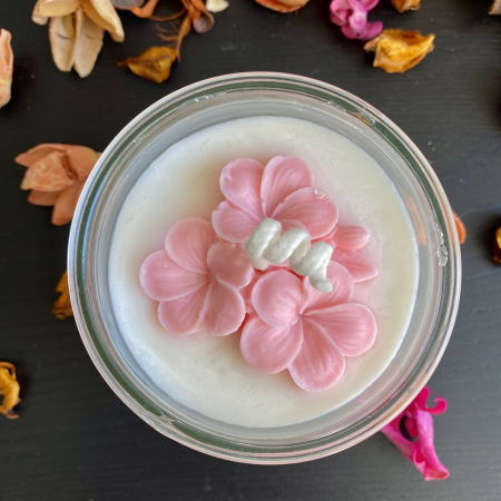 In recipient din sticla - Lumanare parfumata, alba, decorata cu flori roz, in pahar de sticla.